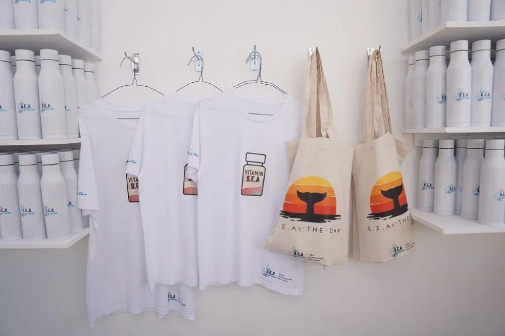 S.E.A. Mission merchandise, including t-shirts, bags, and water bottles.
