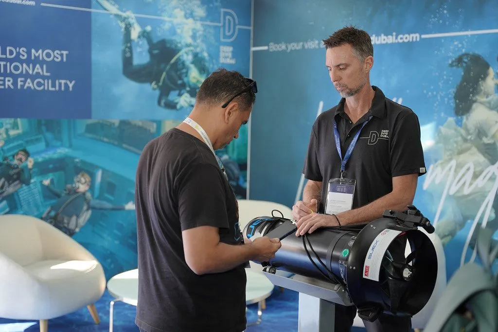 A visitor examines diving equipment at the Deep Dive Dubai stand.
